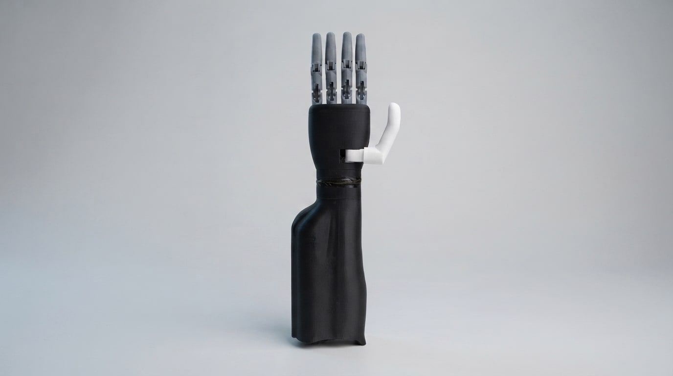 Diego, a black myoelectric prosthetic hand with grey fingers, standing upright on a pale grey background.